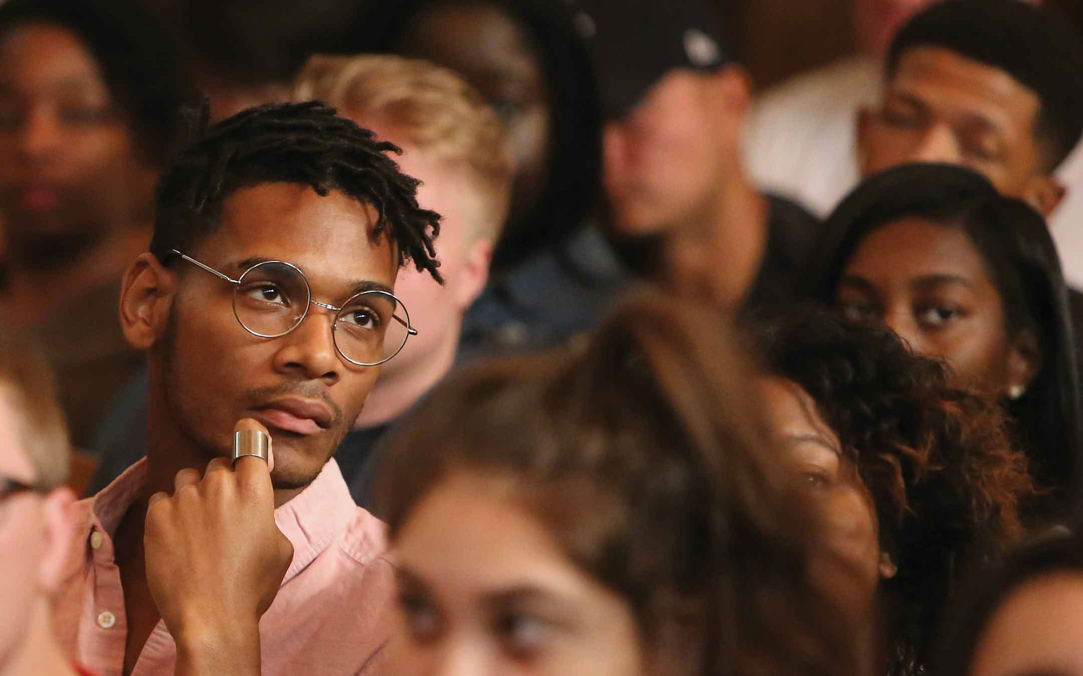 Student looking pensive while sitting in the audience listening to a panel at the 2018 American Dream Reconsidered Conference.