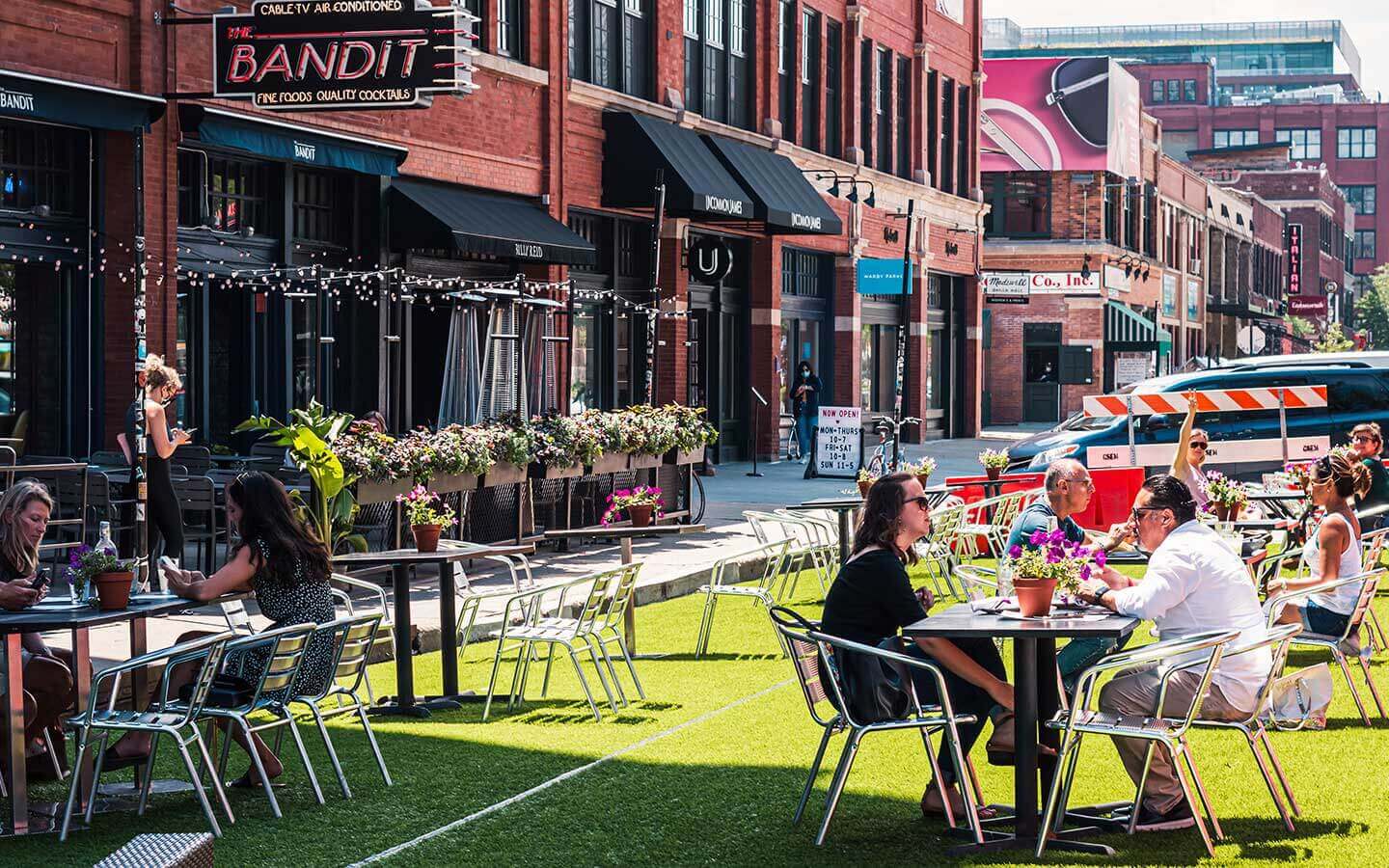 A photo of the west loop neighborhood and dining tables set up on the streets with patrons enjoying a meal in sunshine