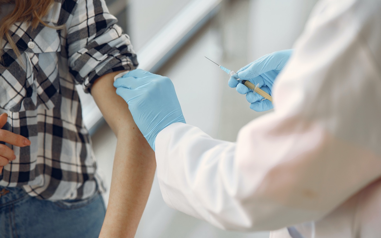 A pharmacist cleans a patient's arm with an alcohol swab before administering a vaccine