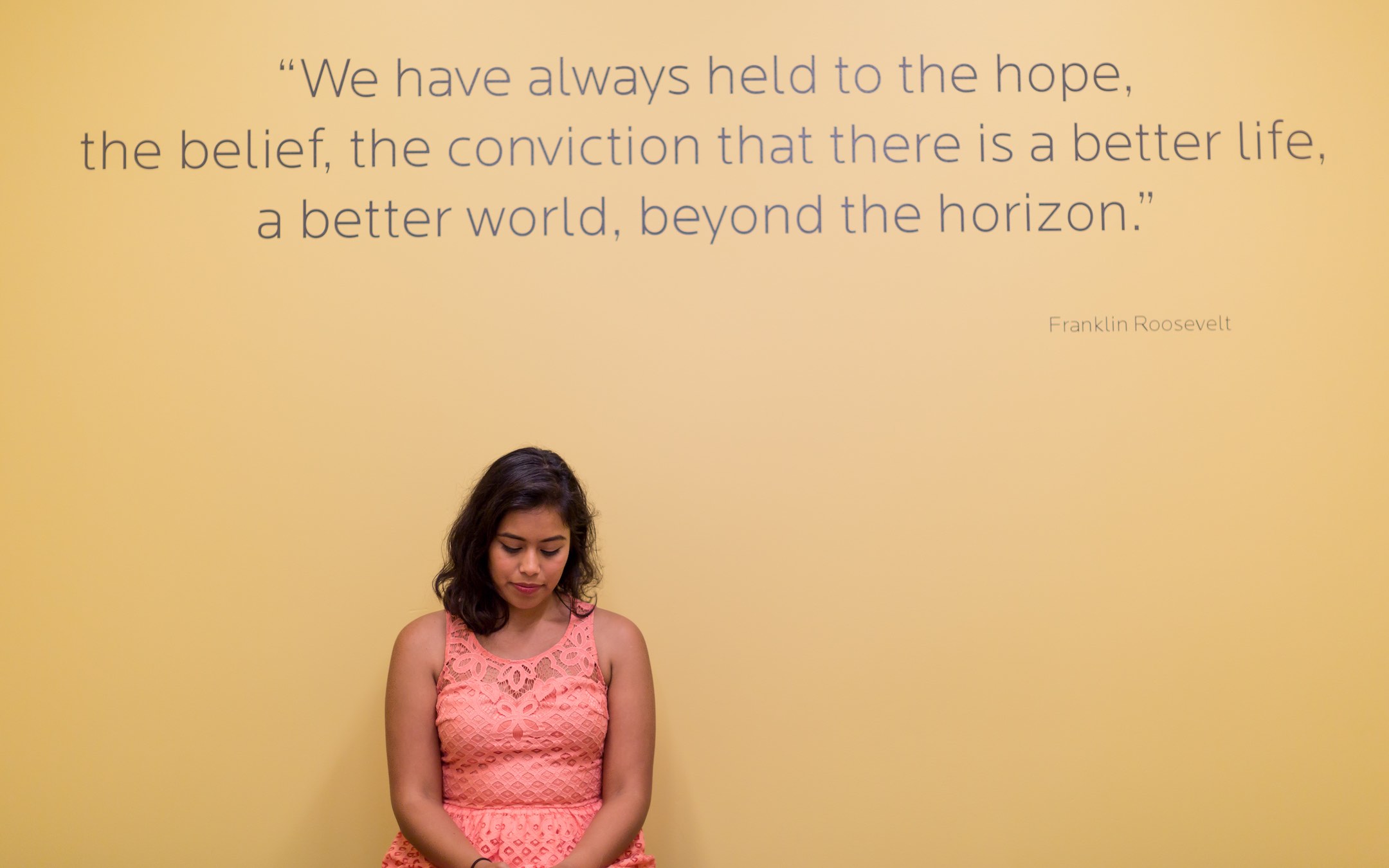 Roosevelt student sitting in front of Franklin Delano Roosevelt quote on wall