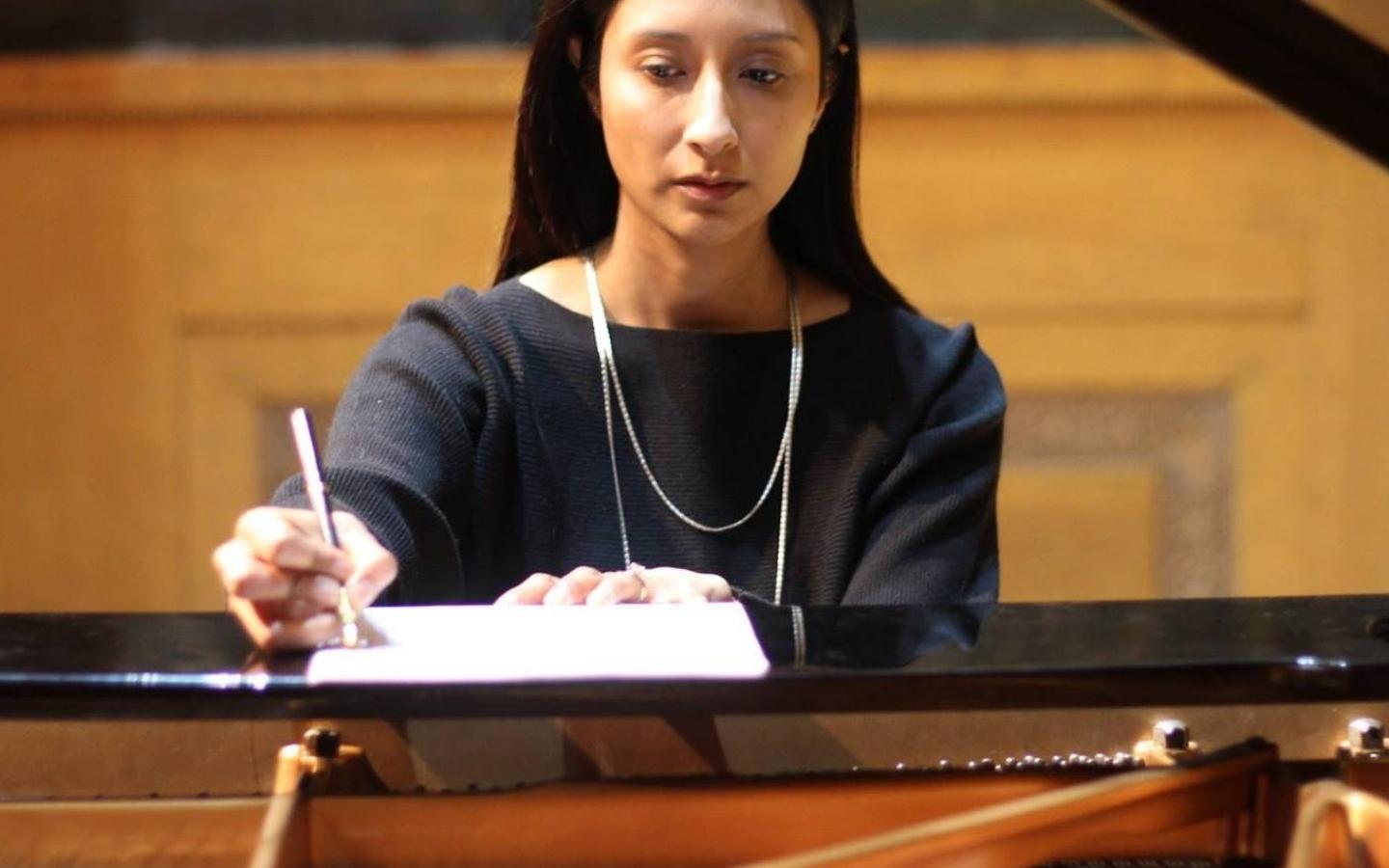 CCPA student Mariana Gomez taking notes by piano