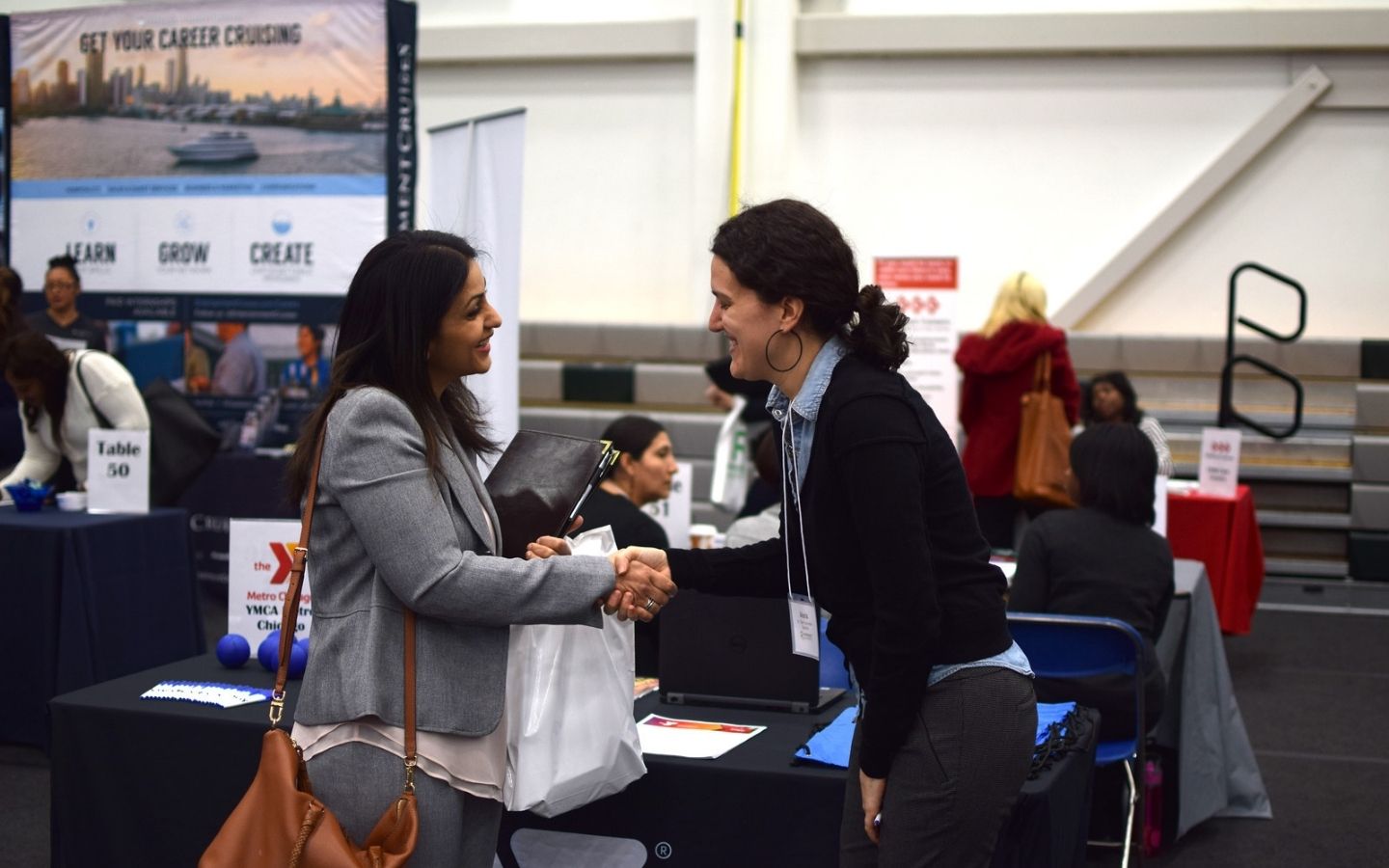 Females in business attire shaking hands at a networking event
