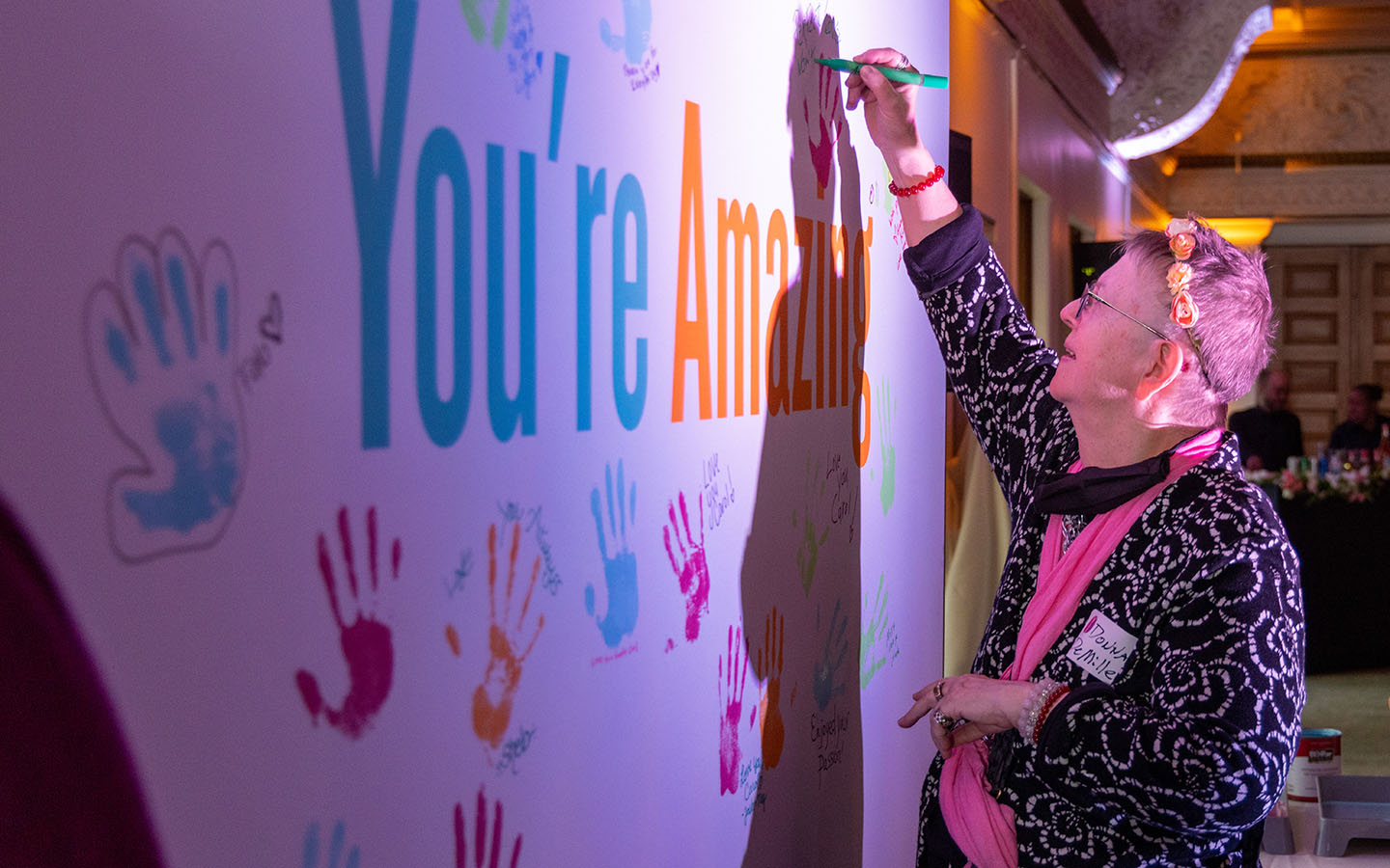 A person signs a wall-sized poster during Dr. Carol Brown's memorial.