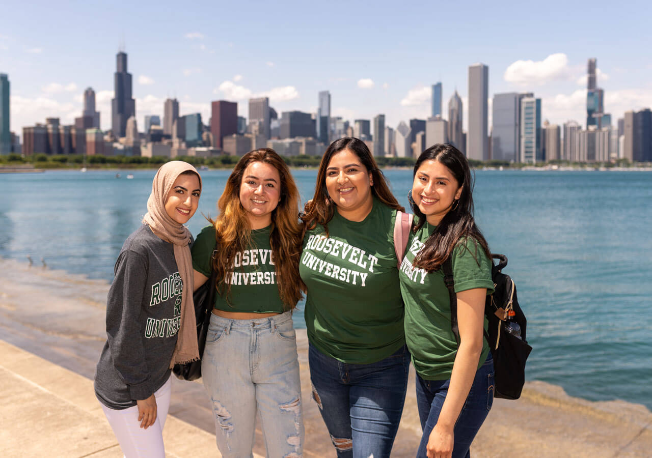 A small group of international students posing by the Lake with the city in the background
