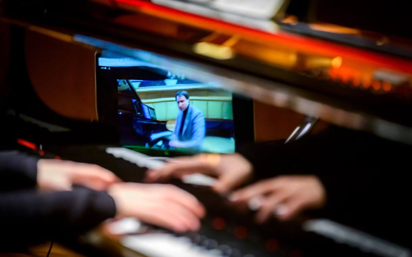 Michal Drewnowski shown playing piano virtually on table while Winston Choi's hands are feature playing along.