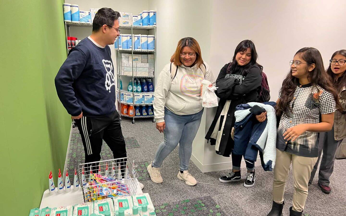 Laker Union Pantry with non-perishable items on display shelves with a group of students standing around them.