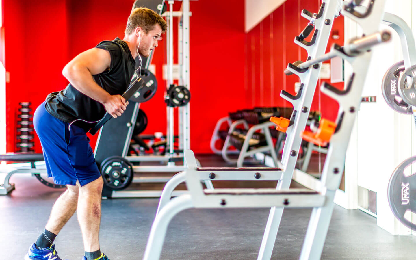 A view of the weight room featuring a participant exercising with weights.