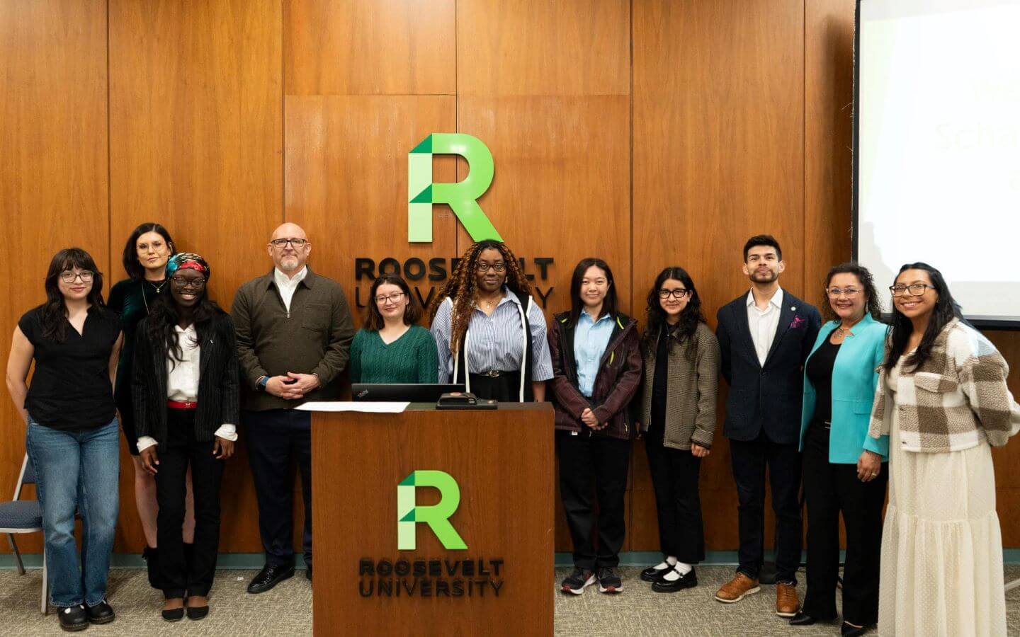 Group standing in front of podium with green Roosevelt logo.