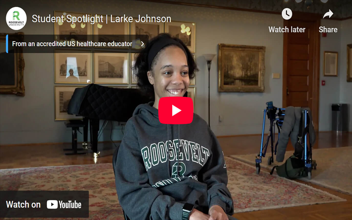 YouTube video still image of Larke Johnson sitting in the Auditorium building wearing a Roosevelt sweatshirt. 