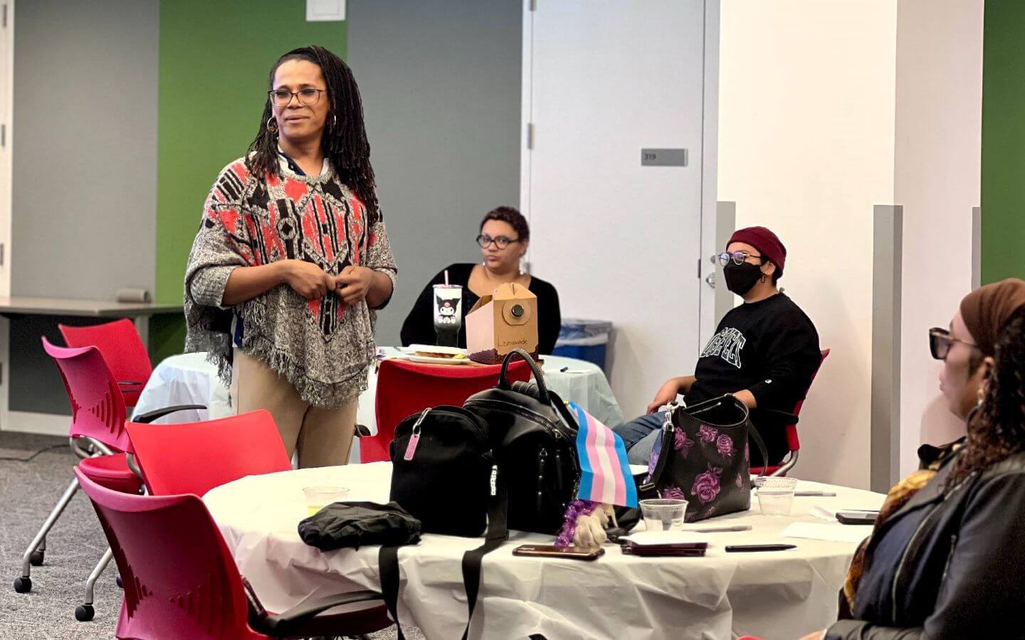 Group of people sitting at tables listening to guest moderator, Dee Dee Waters at the Transgender Day of Remembrance vigil