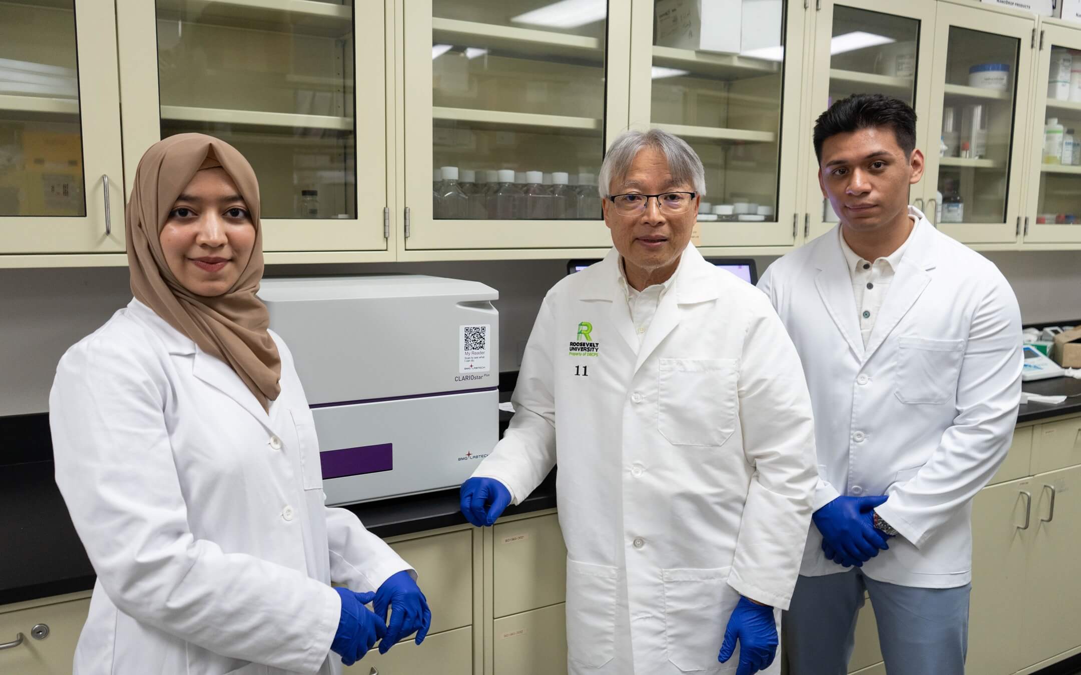Science or Pharmarcy students and a faculty member standing by laboratory equipment