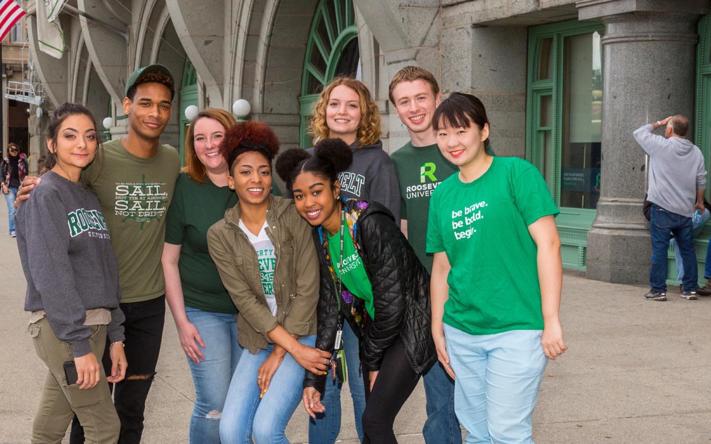 Eight students in Roosevelt shirts stand near the Michigan Ave Auditorium entrance