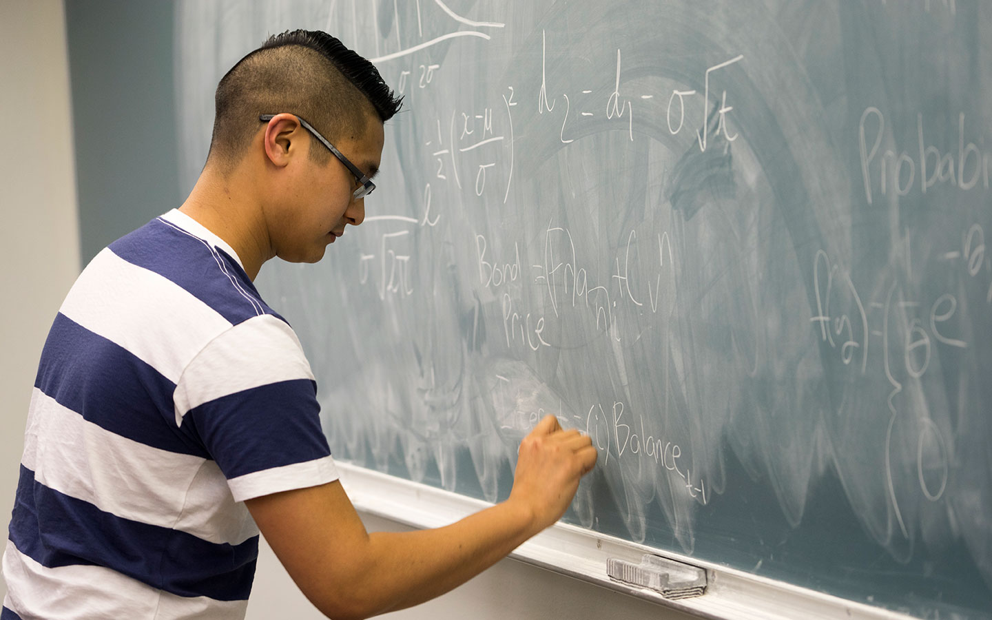 Student at chalkboard doing equations - actuaries