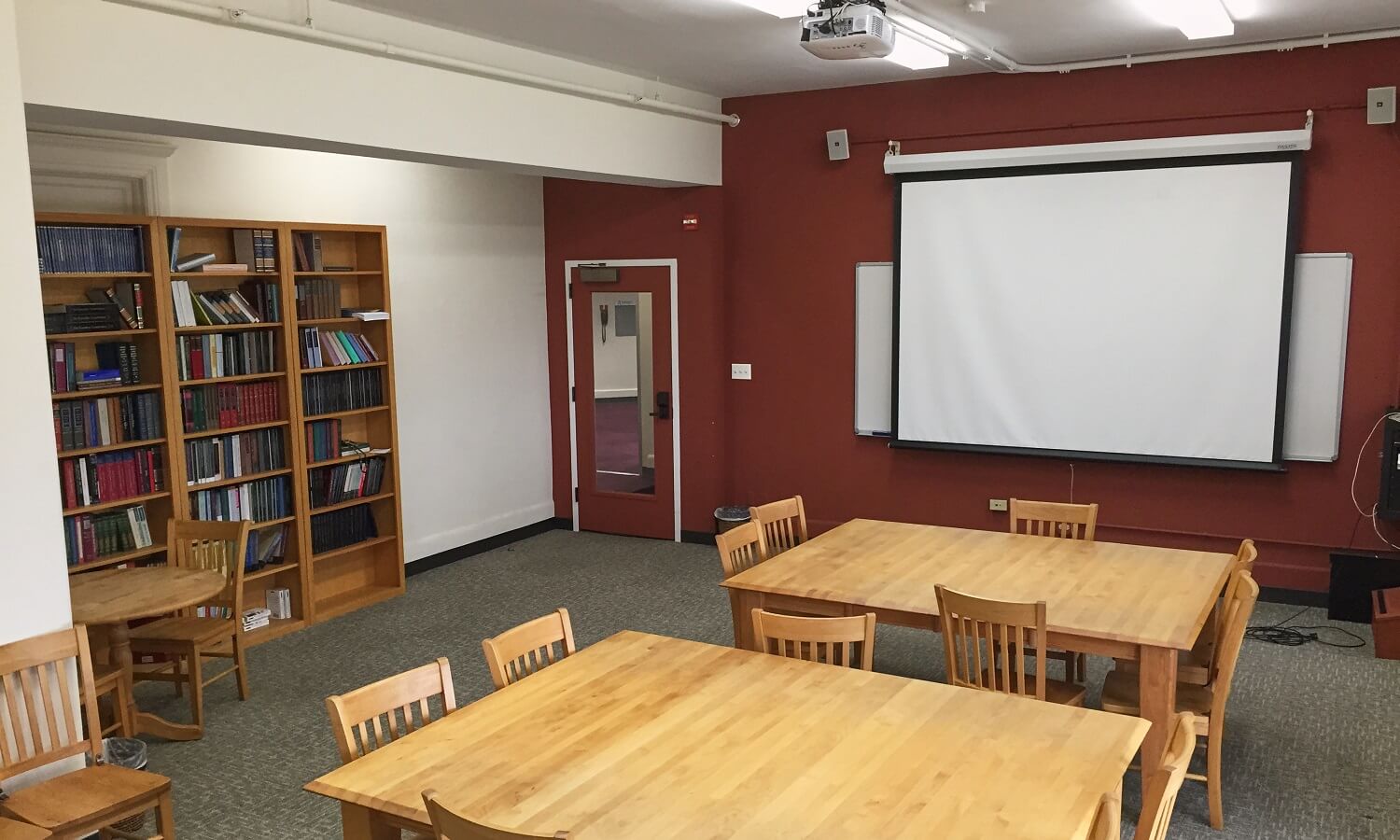 Reading Room with tables and chairs, bookshelves, and presentation screen.