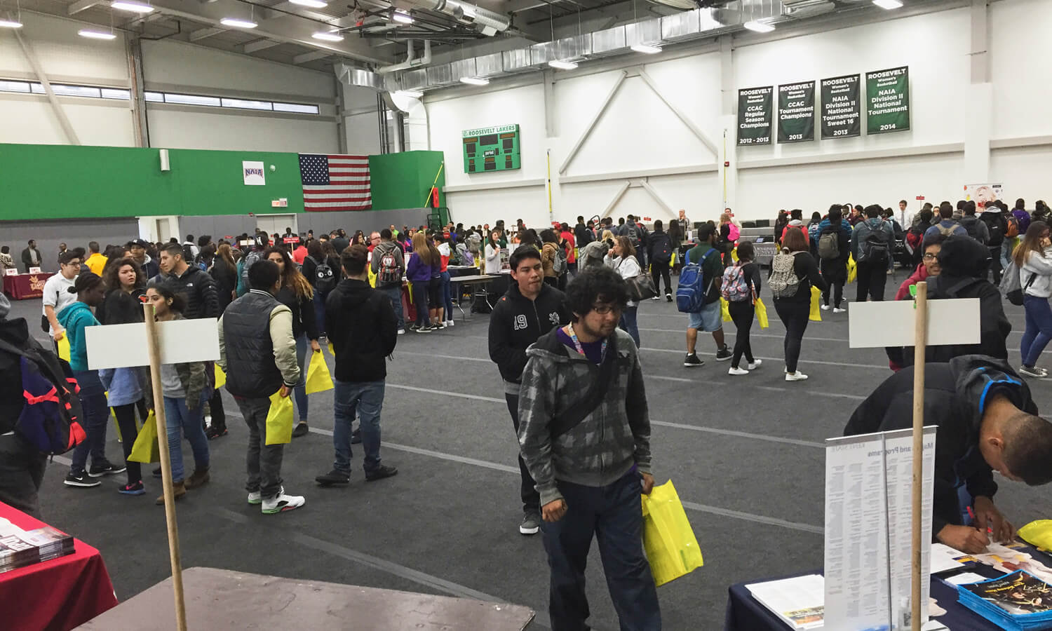 Large room with people standing around tables in an exhibit setup.