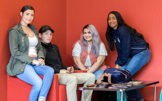 four students in front of a red wall