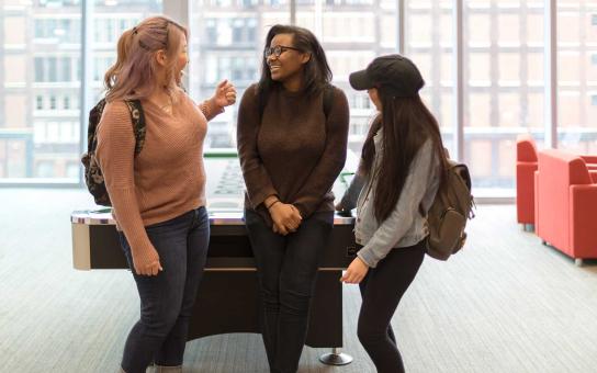 three students in lounge in front of pool table