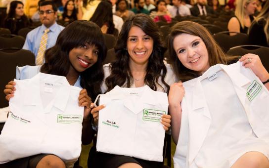 Pharmacy students at graduation with white coats