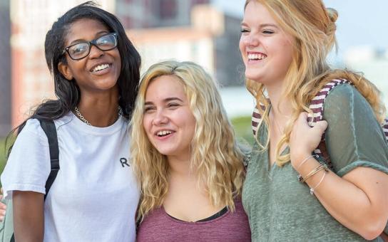 Three students laughing having fun in the city