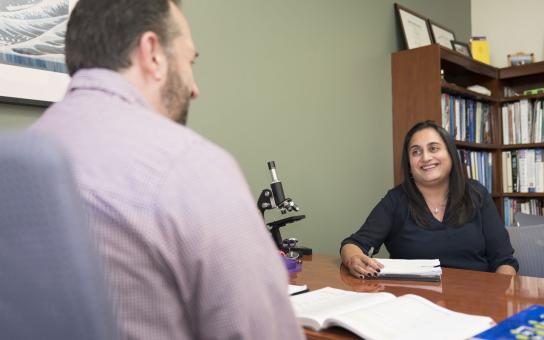 Student sitting across from an instructor in an office setting.