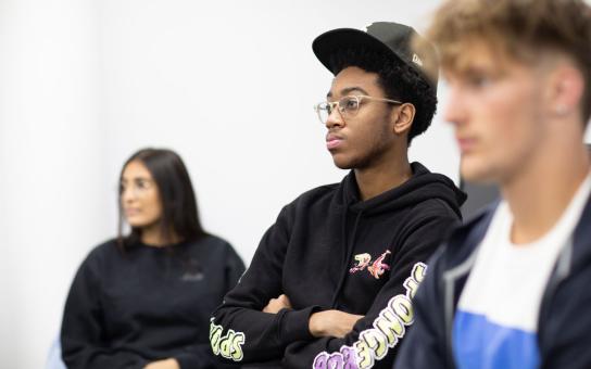 A trio of students standing in a classroom next to a whiteboard.