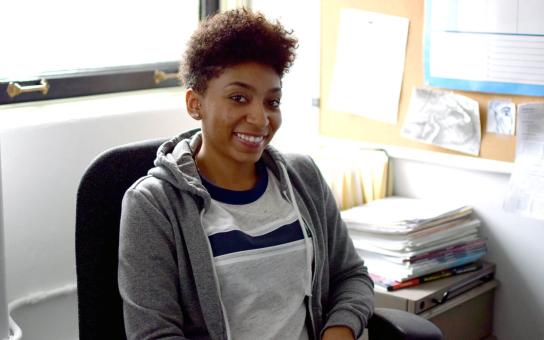 Smiling person sitting on an office chair in an office with lots of natural lighting