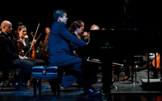 Pianist performing a concerto accompanied by a symphony orchestra