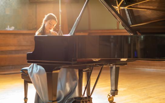 Female pianist performing in a naturally well-lit room with sunlight illuminating the pianist from behind