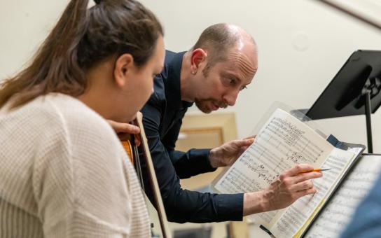 Music faculty points to a specific spot on the music score showing a student something