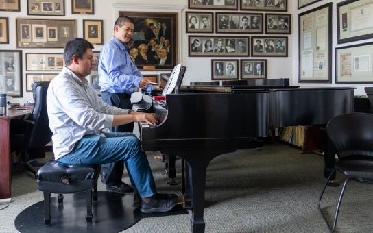 Winston Choi instructing a student on a baby grand piano