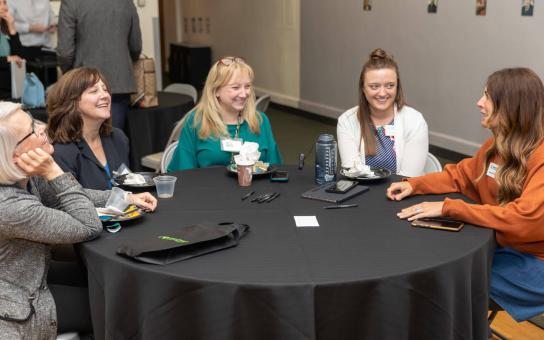 5 people around a table at a conference in conversation