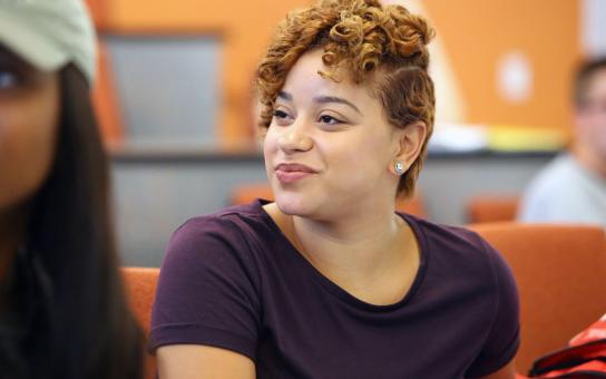 Student sitting in a Wabash Building lecture hall with orange walls