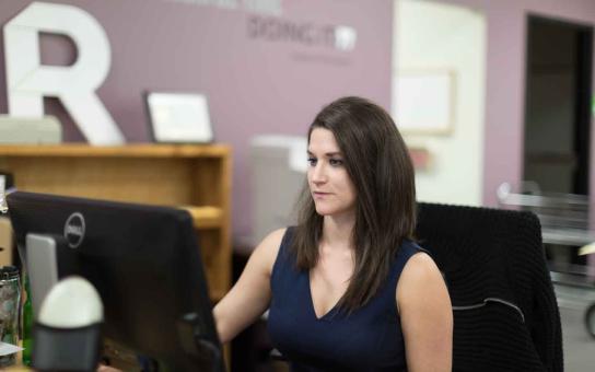 Woman sitting at a computer in an office setting.