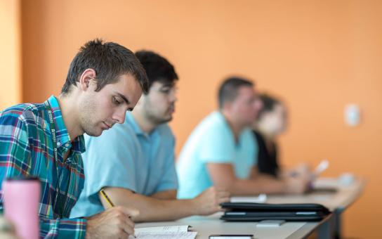 Students sitting in a row and taking notes from a lecture