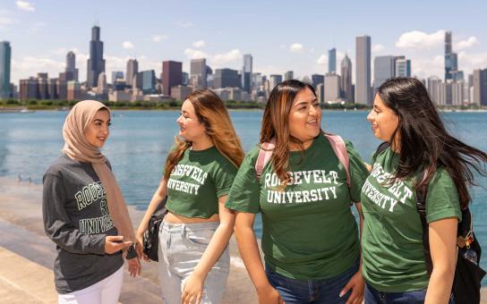 Four students in Roosevelt shirts with the Chicago skyline in the background
