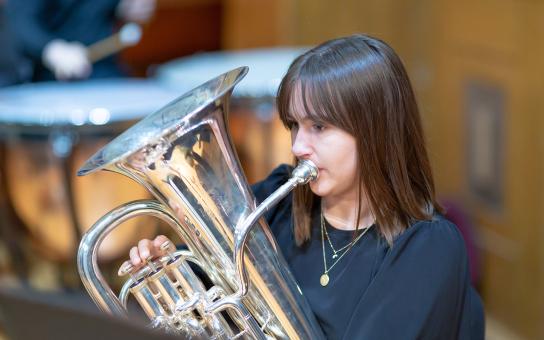 Student in black shirt playing a tuba.