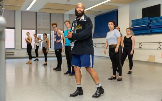 Students a line practicing dance while looking towards an instructor