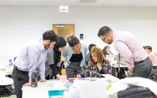 A group of students gathers around a table at the Schaumburg Campus