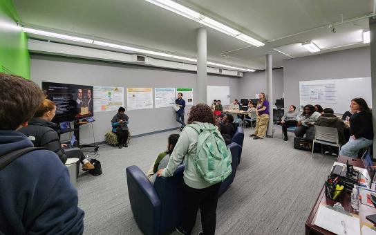 Students and staff in the STEM Center watching a research presentation