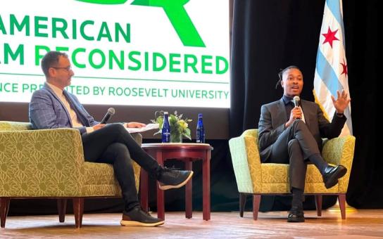 Political Science professor David Faris on stage sitting on stage engaged in a discussion with vice chair of the Democratic National Committee, Malcom Kenyetta