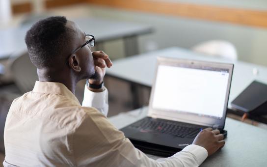 A student stares pensively at a laptop