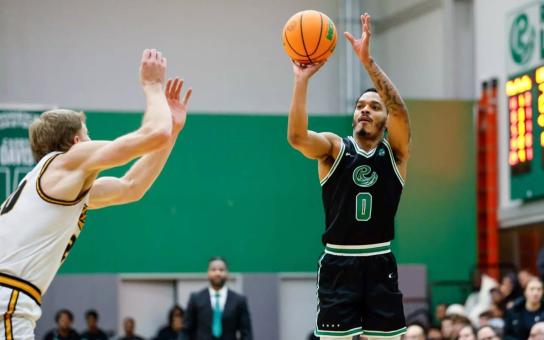 Roosevelt basketball player shooting a basketball over an opponent with defensive arms raised.