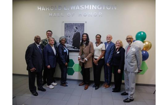 Honored guests, speakers, alumni, staff, and RU President stand in front of the Harold L. Washington Hall of Honor picture and dedication plaque.  