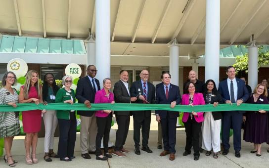 RISE Ribbon Cutting at Schaumburg Campus with several people standing behind a green ribbon