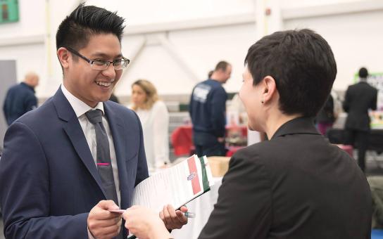 Student exchanges business card with employer at career fair