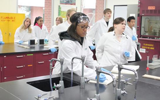 Pharmacy students at a lab bench taking notes during a lecture