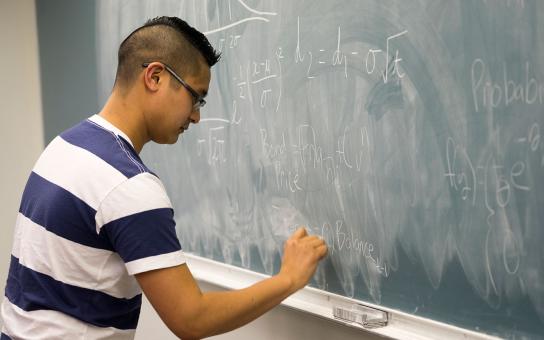 Student at chalkboard doing equations - actuaries