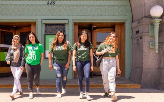 Five Roosevelt students smiling as they walk out of the Auditorium building on a sunny day