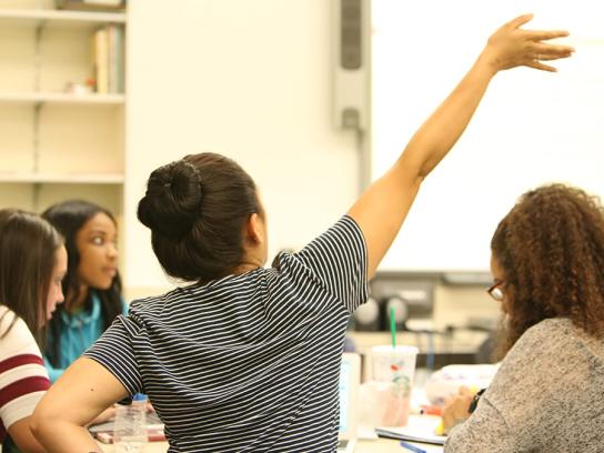 Student raising hand in class-VisitingNonDegree-TuitionAndAid