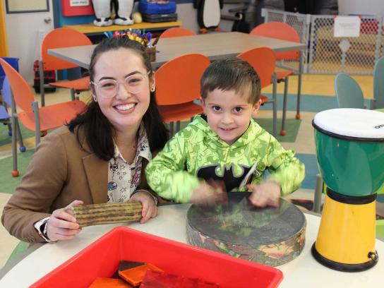CCPA student participating in Sharing Notes program with child playing drum